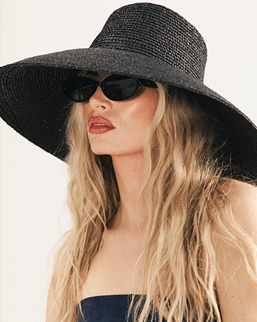 Woman wearing a black sun hat and sunglasses on a white background