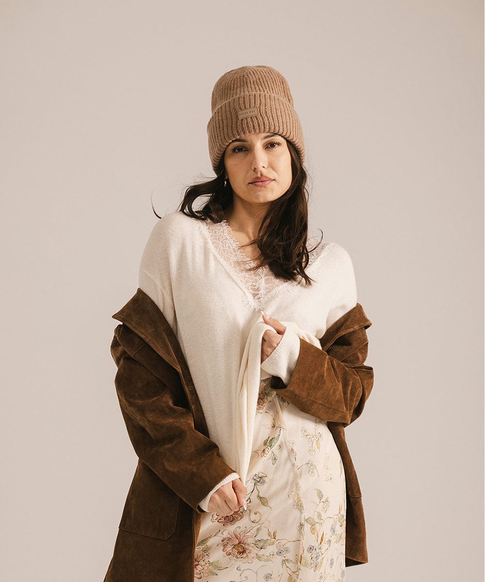 Woman wearing a brown coat and knit hat against a plain background #color_brown
