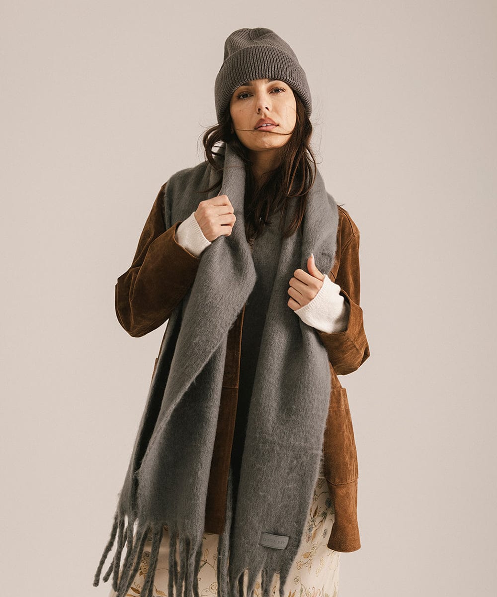 Woman wearing a gray scarf and beanie against a plain background #color_grey