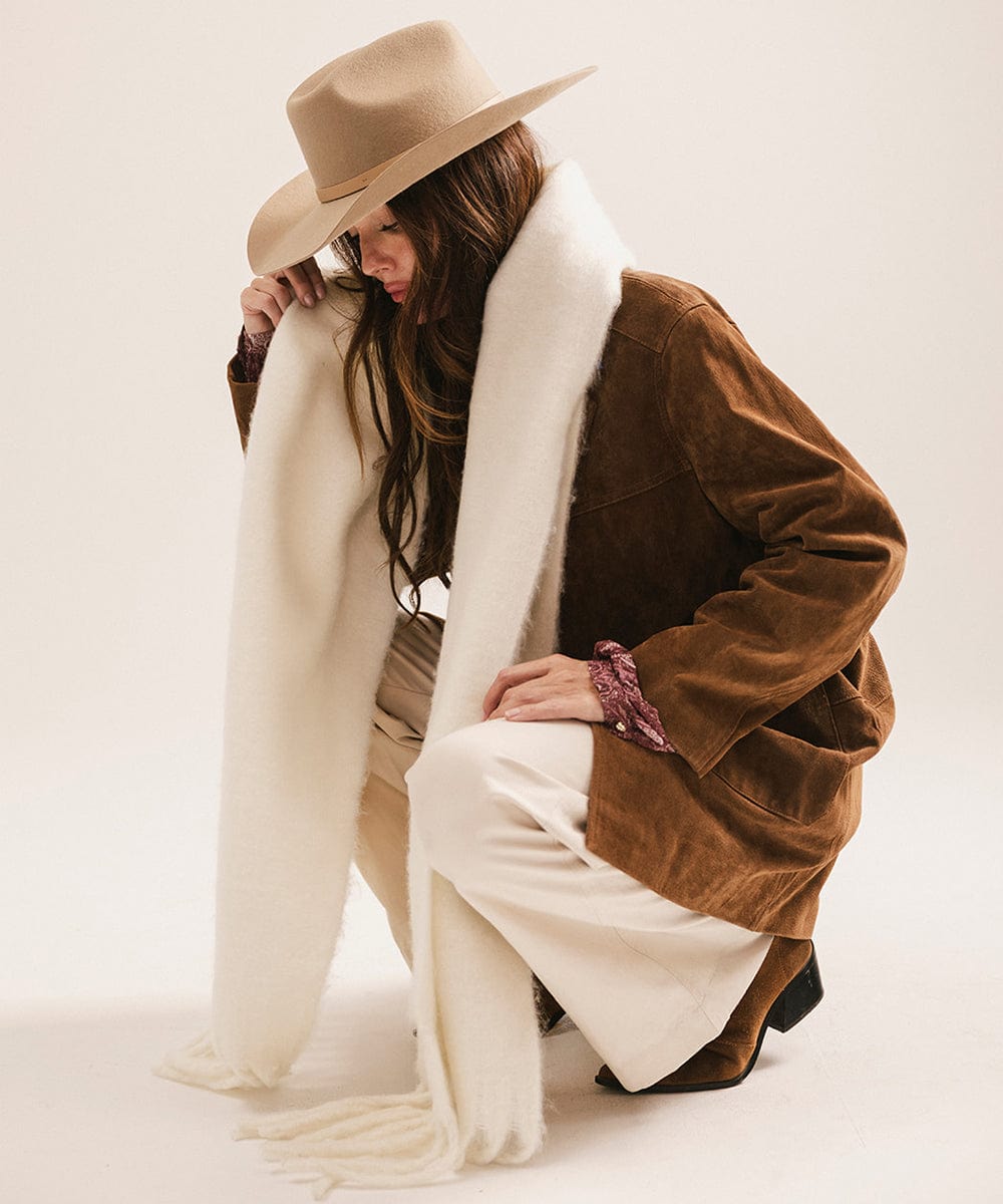 Woman wearing a brown coat with white fur lining and a beige hat, sitting on a white background. #color_off white