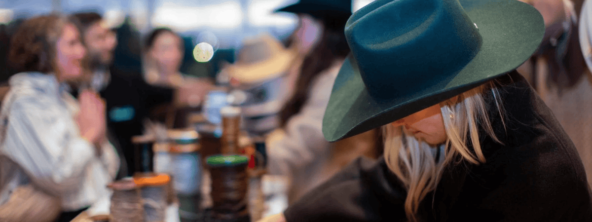 Person wearing a green hat at a Custom Hat Bar with Gigi Pip with blurred background