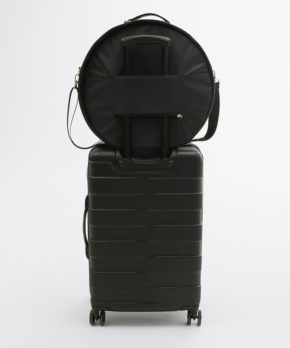 A black round hat travel case on top of a black suitcase against a plain background #color_black