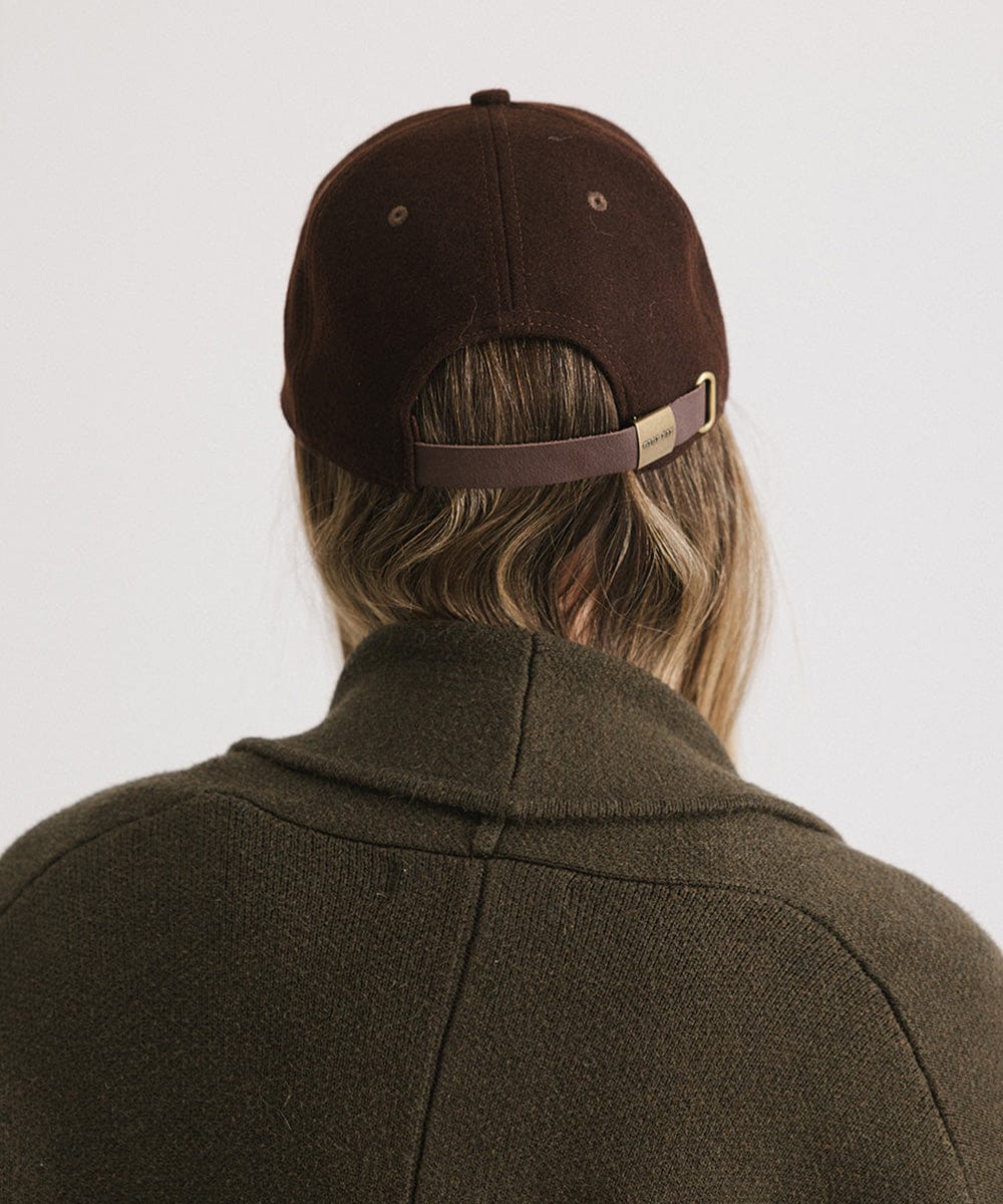 Person wearing a brown cap and a brown coat against a plain background #color_brown