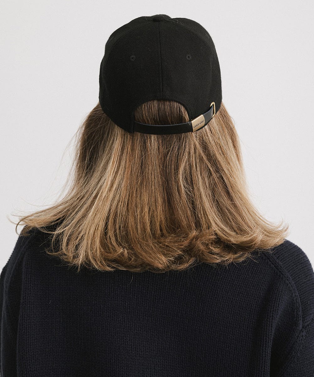 Person wearing a black cap and a black sweater against a plain background #color_black