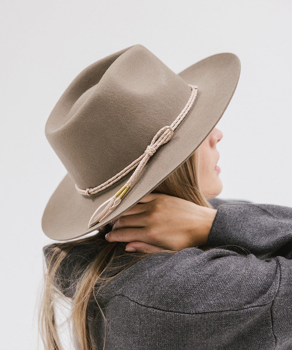 Woman wearing cowboy hat with a beige lasso braided hat band and a grey sweater, facing sideways against a plain background #color_beige