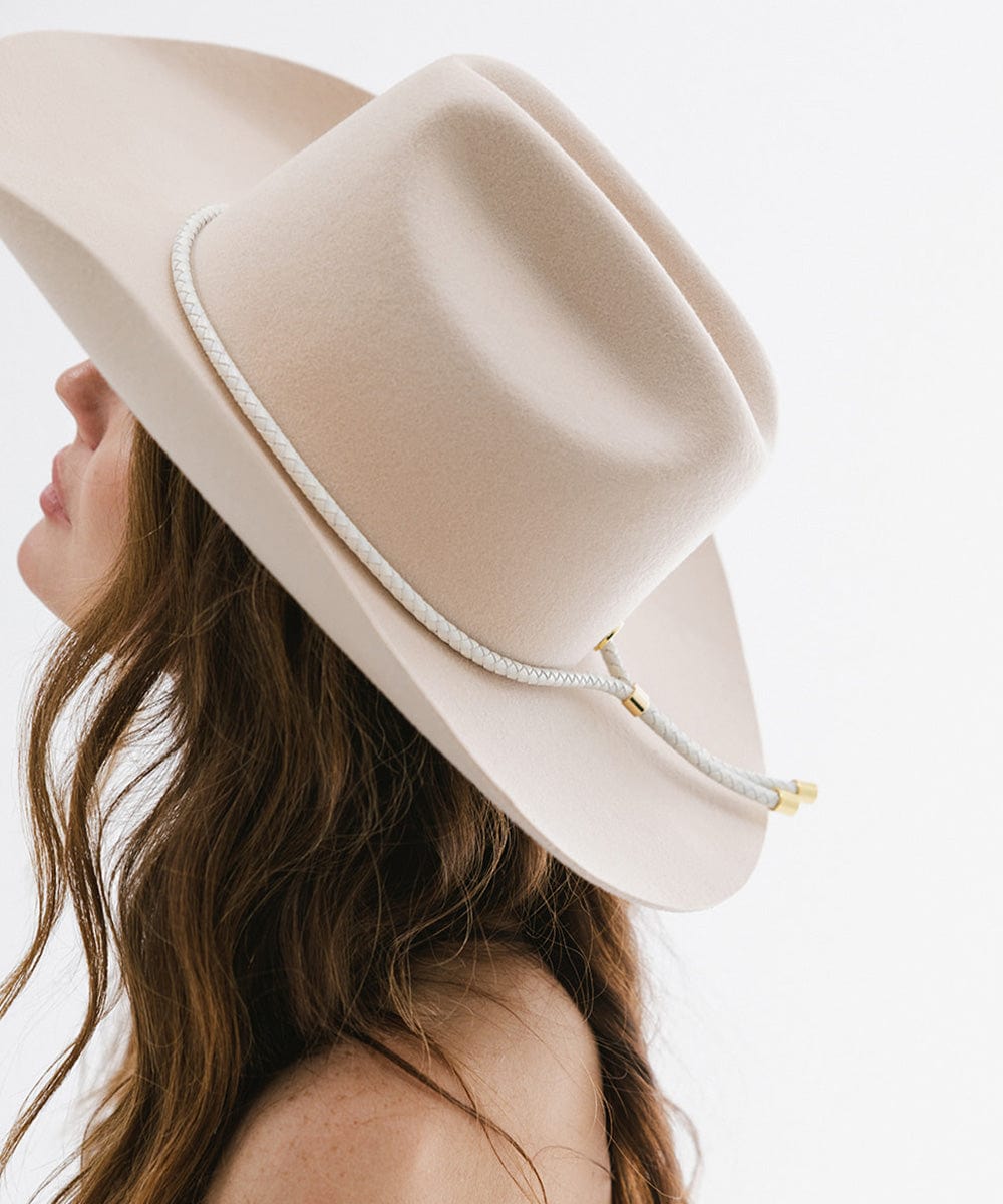 Woman wearing a cream hat with an ivory colored braided bolo hat band, facing sideways against a plain background #color_ivory