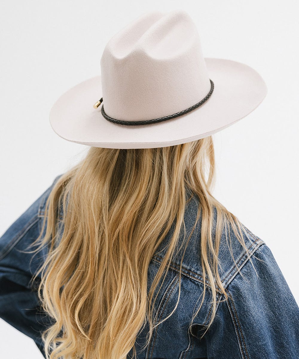 Woman wearing a cream hat with a black braided hat band and a denim shirt, facing behind against a plain background #color_black