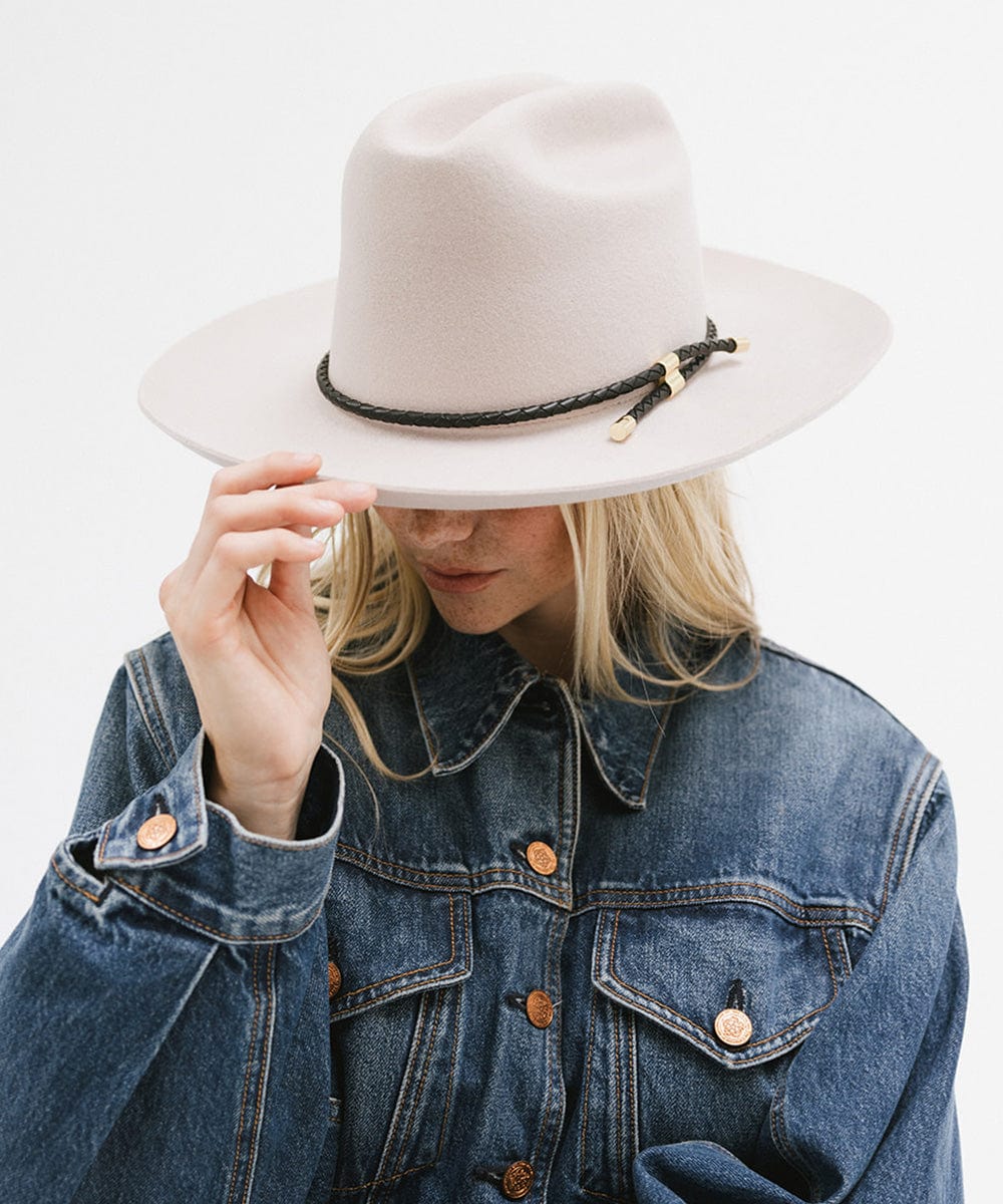 Woman wearing a cream hat with a black braided hat band and a denim shirt against a plain background #color_black