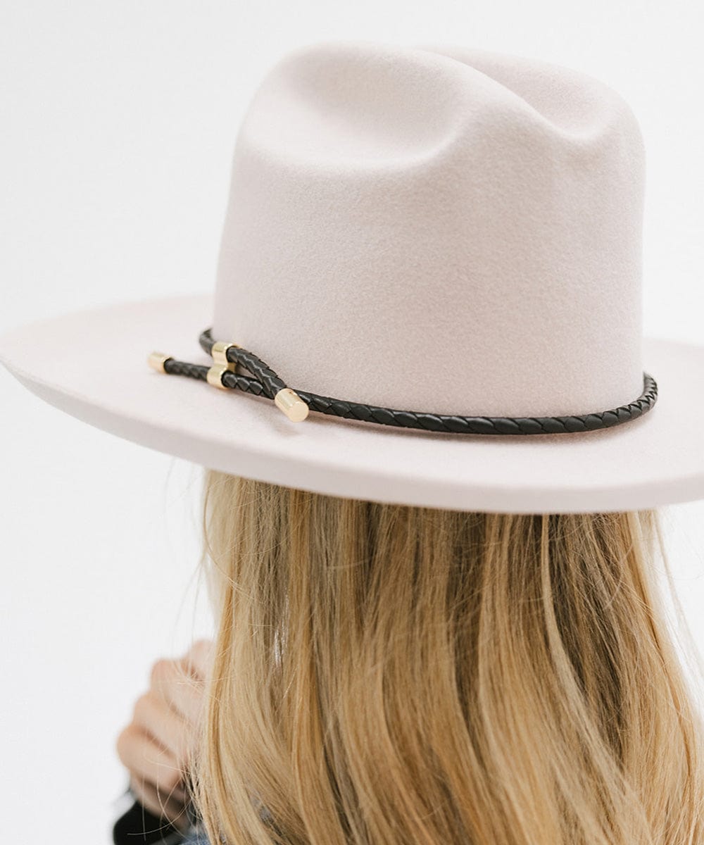 Woman wearing a cream hat with a black braided hat band facing behind against a plain background #color_black