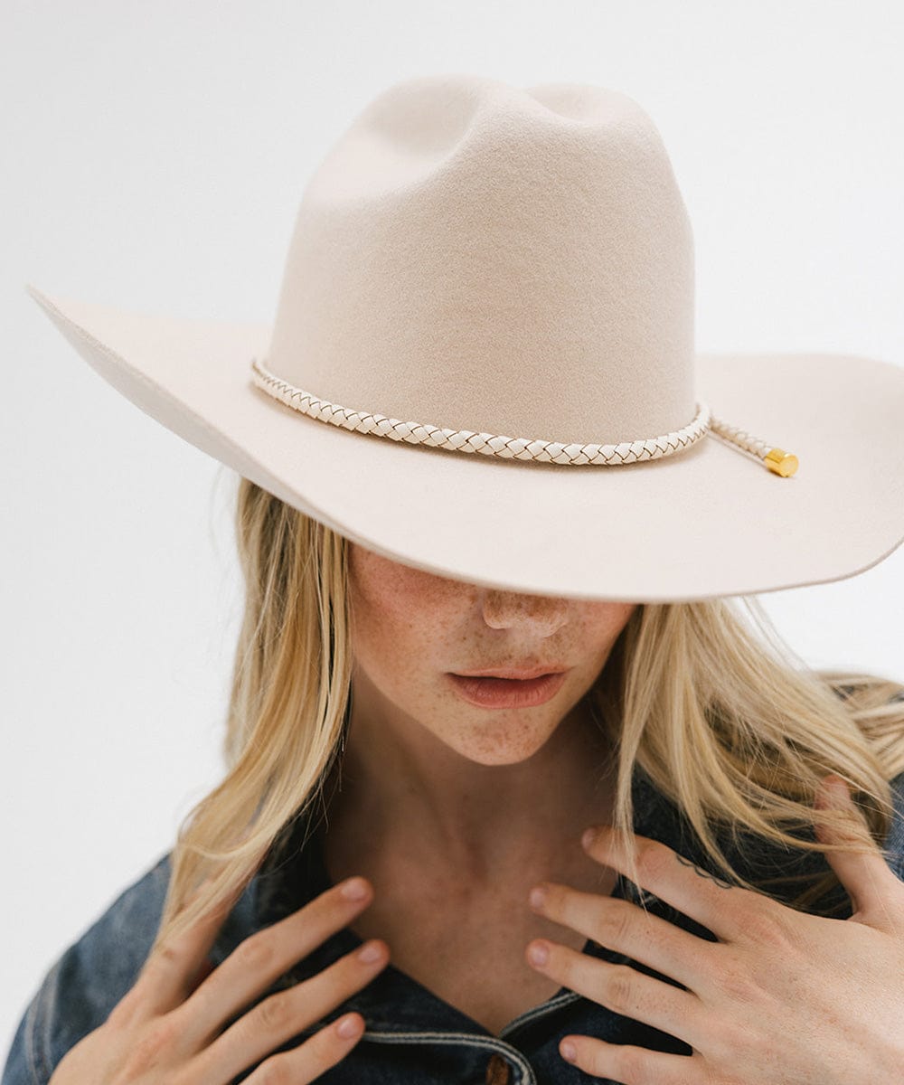 Woman wearing a cream hat with an ivory colored braided hat band and a denim shirt against a plain background #color_ivory