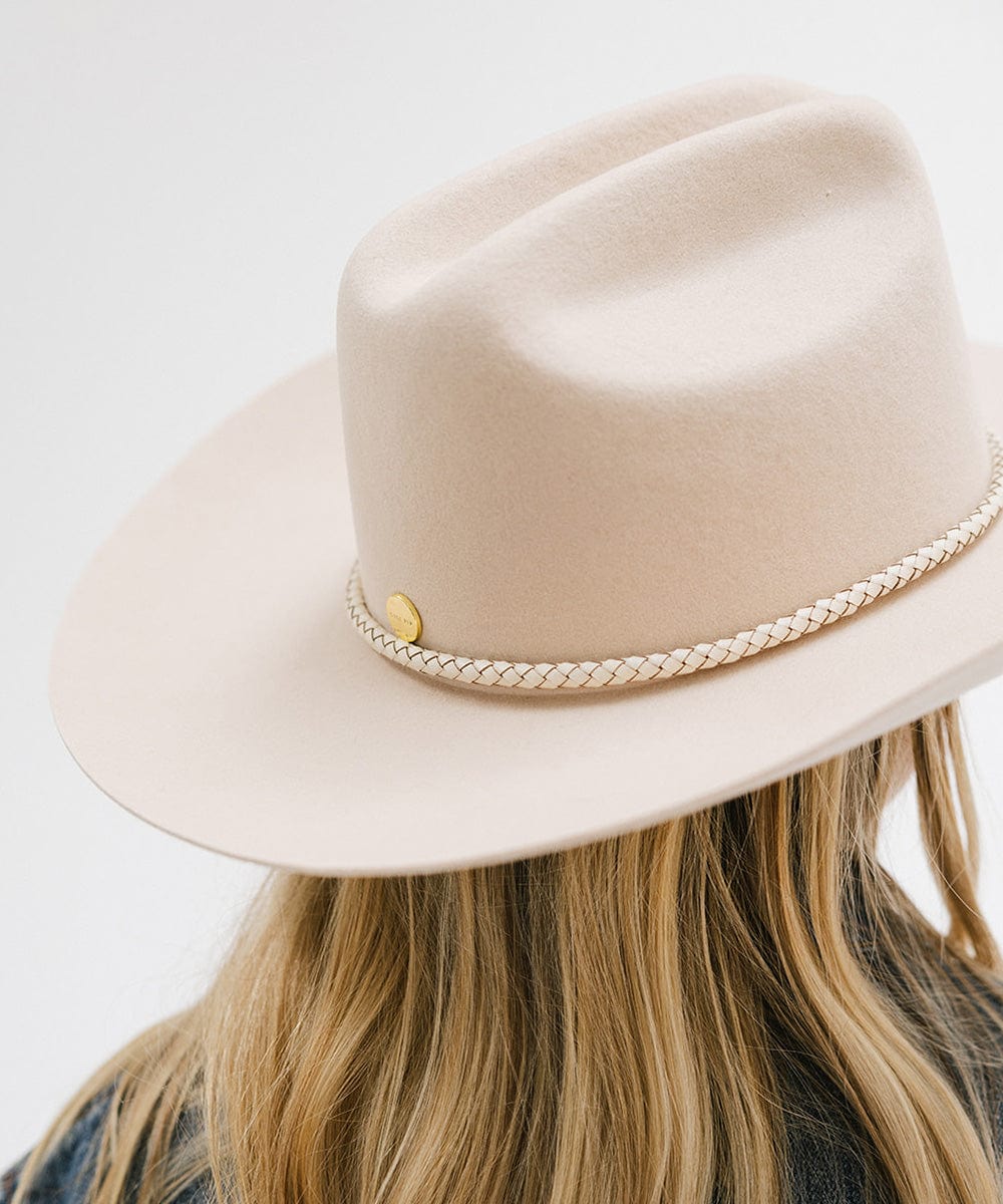 Woman wearing a cream hat with an ivory colored braided hat band and a denim shirt, facing behind against a plain background #color_ivory