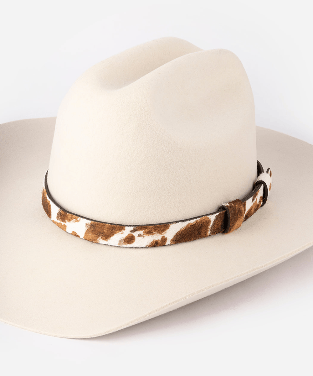 Beige cowboy hat with a cowhide decorative band on a white background #color_brown