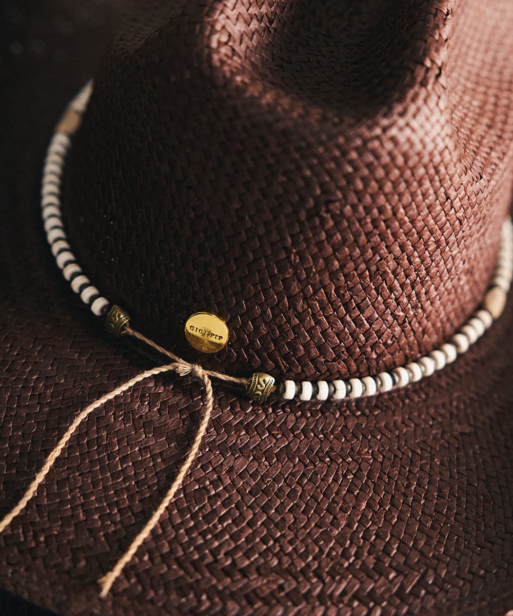 Close-up of a brown woven hat with a beaded band on top #color_brown-white