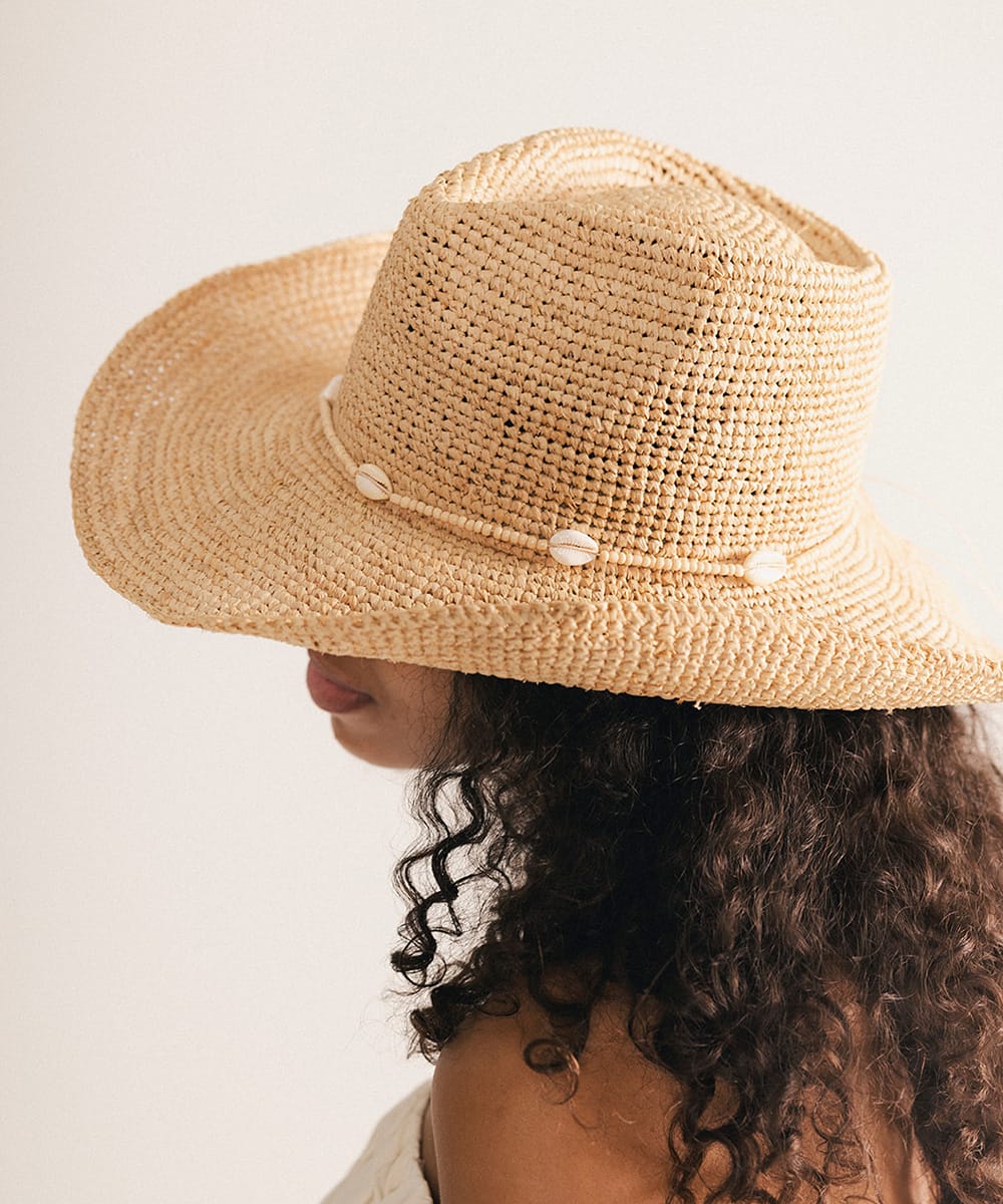 Woman wearing a straw hat with a decorative band against a plain background #color_cream
