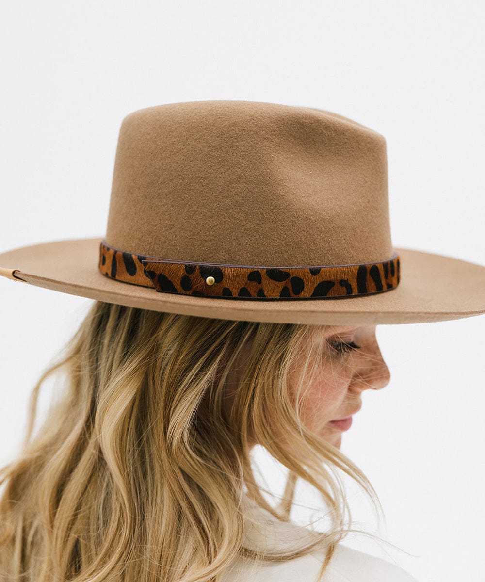 Woman wearing a beige hat with a dark brown leopard print hat band facing sideways against a plain background #color_dark brown
