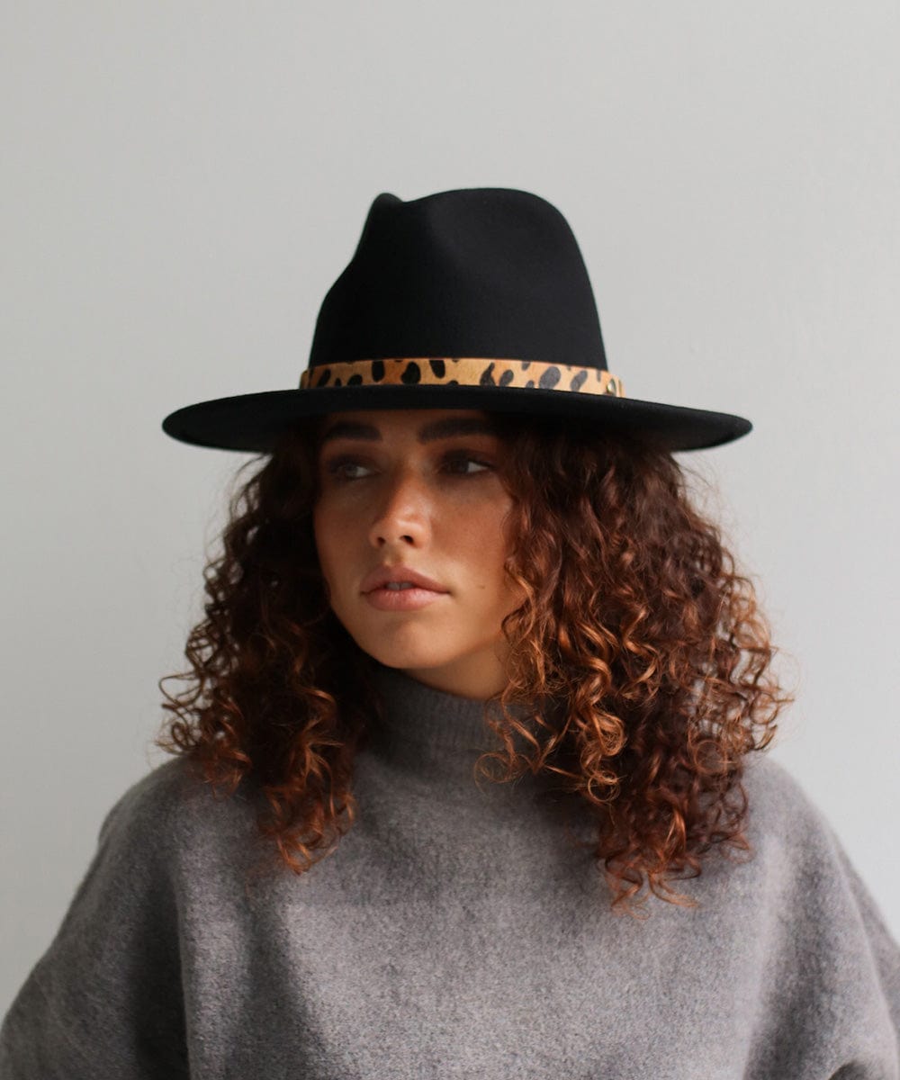 Woman wearing a black hat with a tan leopard print hat band and a grey t-shirt against a plain background #color_tan