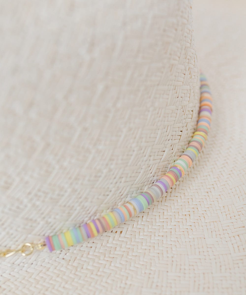 Close up image of a white hat with a multi colored beaded hat band #color_multi
