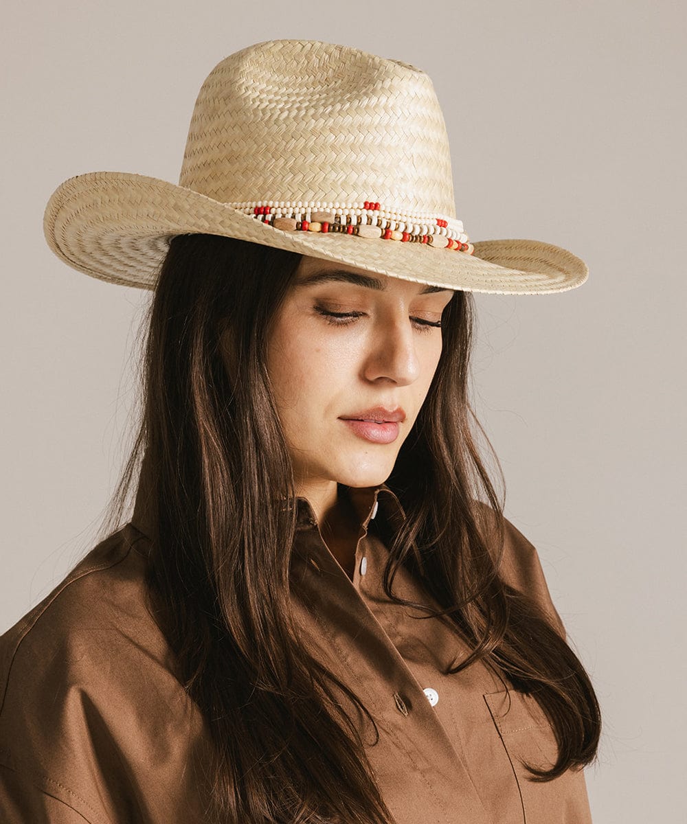 Woman wearing a beige hat with a natural colored layered beaded hat band and a brown shirt against a plain background #color_natural