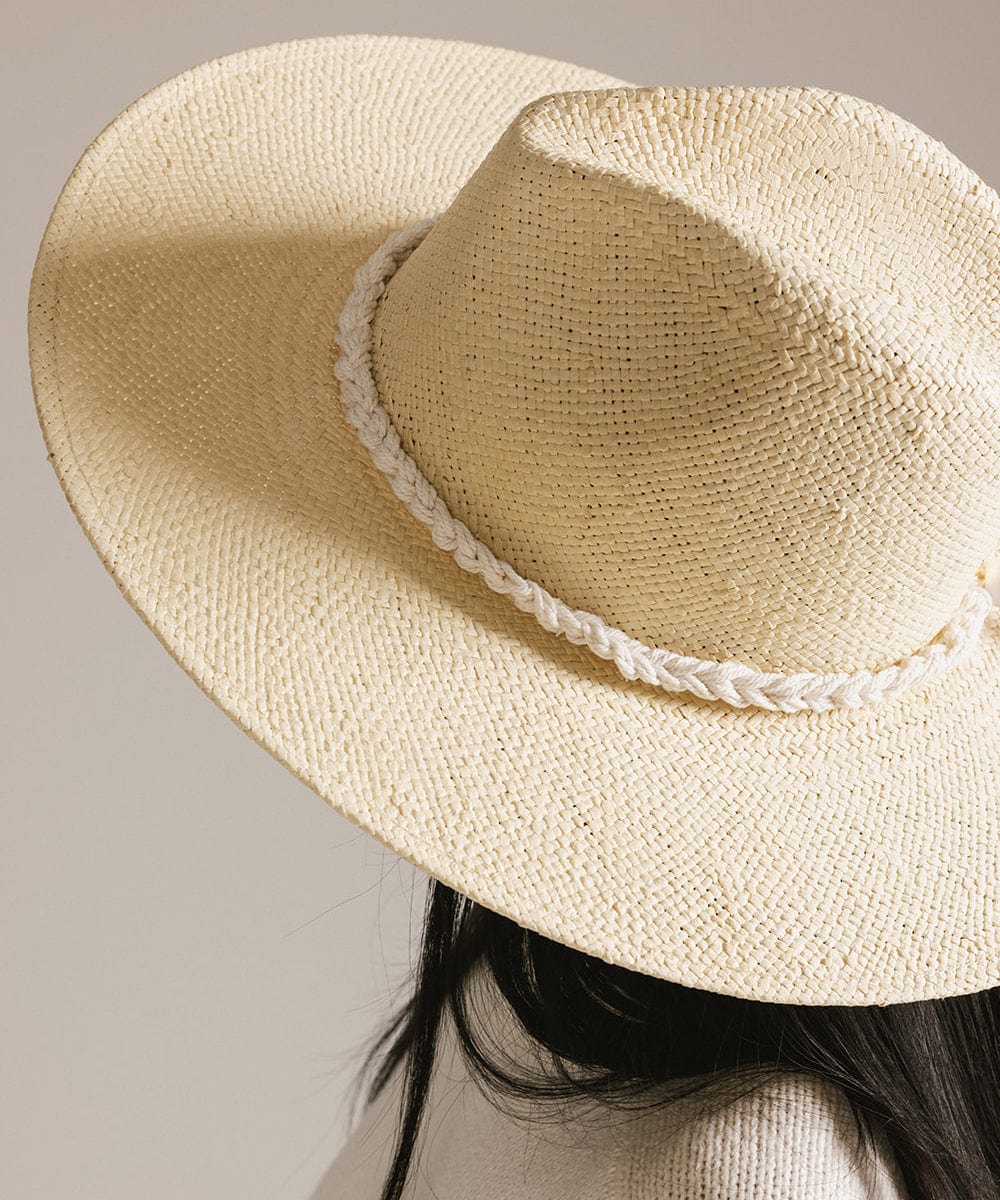 Close up image of a person wearing a beige cap with a natural white colored braided rope hat band against a plain background #color_natural white