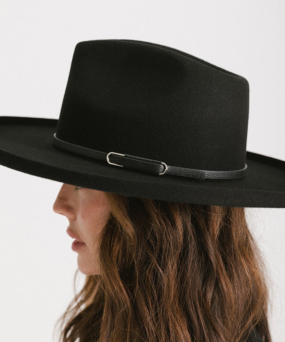 Woman wearing a black wide-brimmed hat with a black hat band, facing sideways against a plain background #color_black