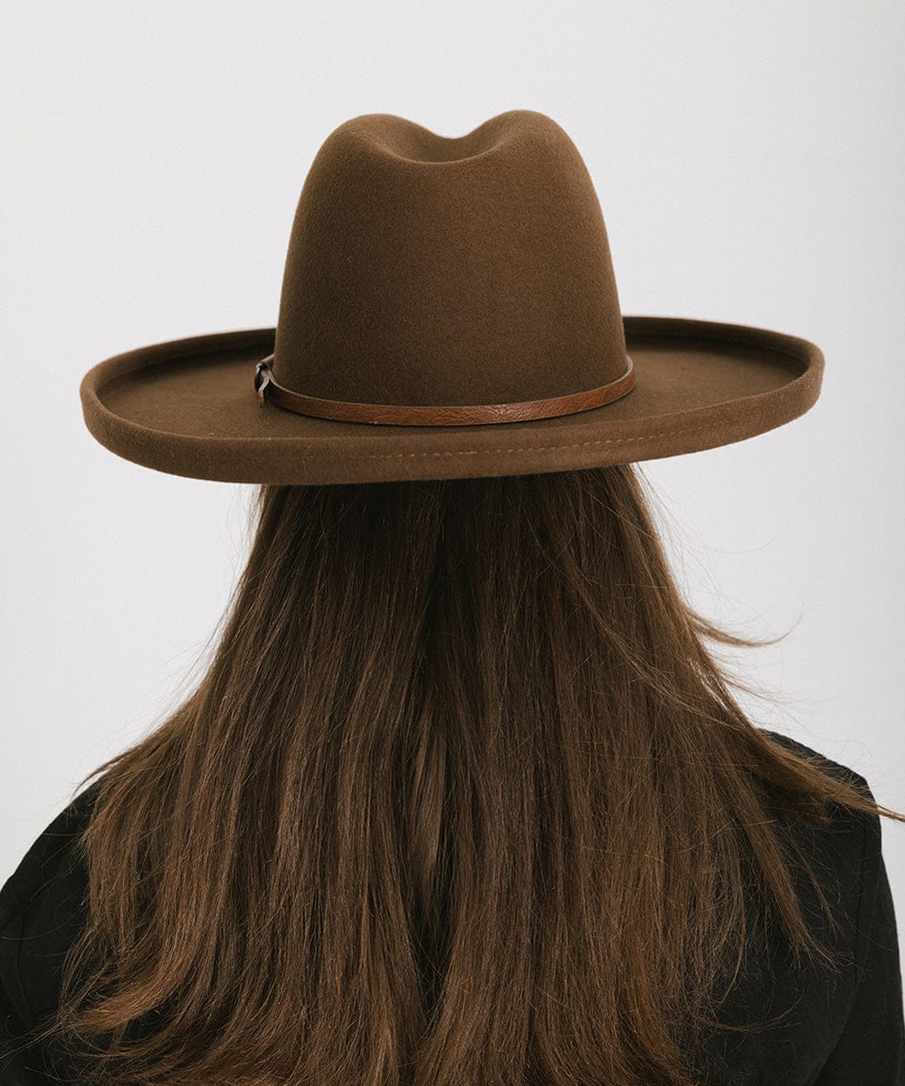 Woman wearing a brown wide-brimmed hat with a brown hat band, facing behind against a plain background #color_brown