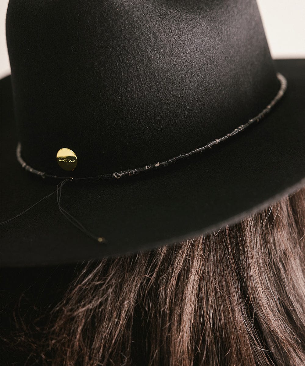 Close-up of a black fedora hat with a gold button on a white background #color_black obsidian