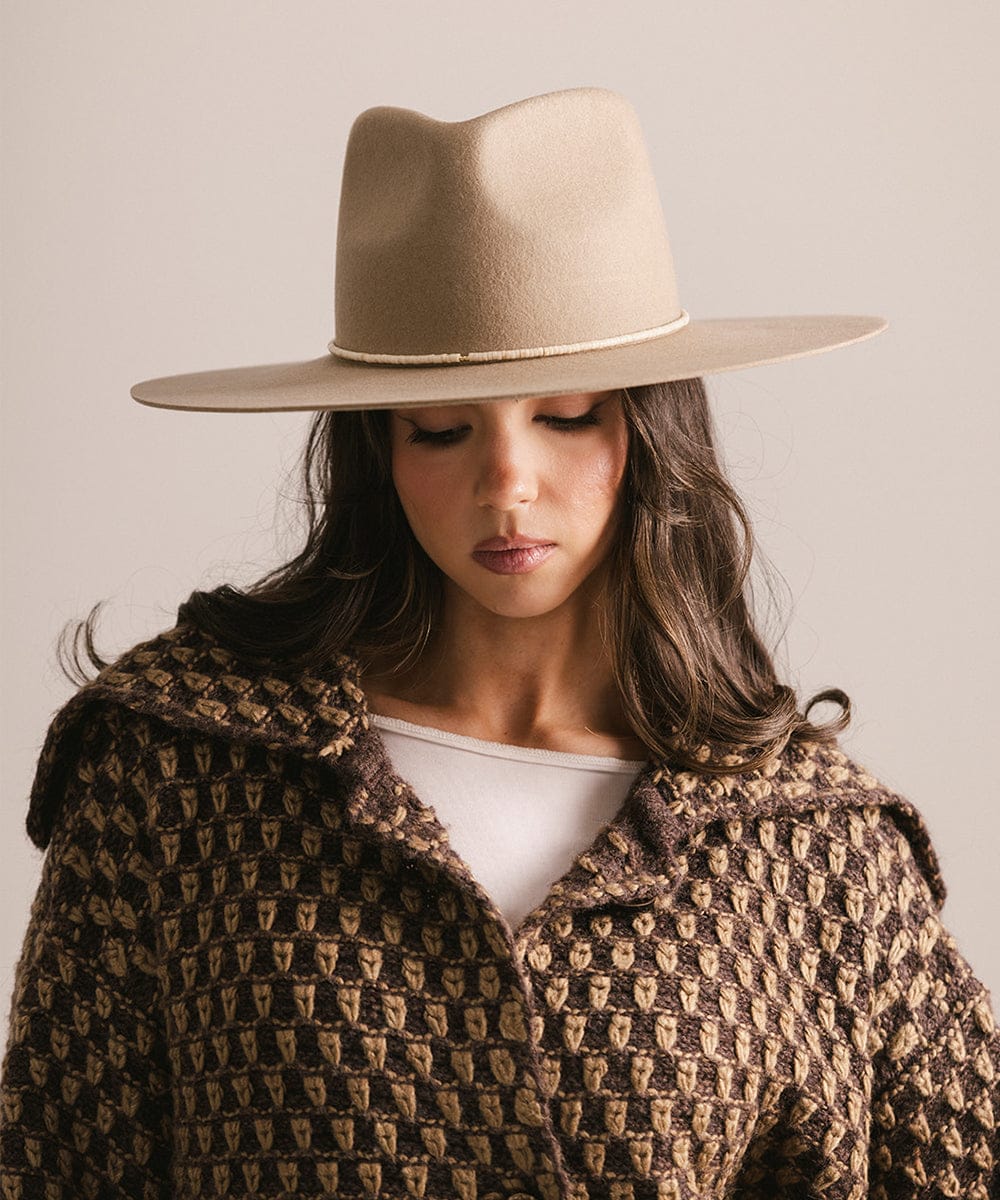 Woman wearing a beige hat and patterned coat against a neutral background #color_natural fossil