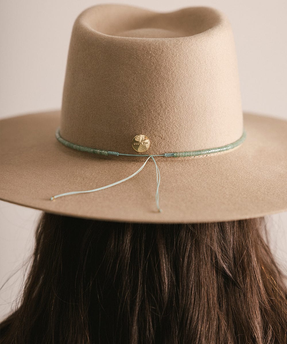 Beige hat with a decorative band and button on a neutral background #color_green jade