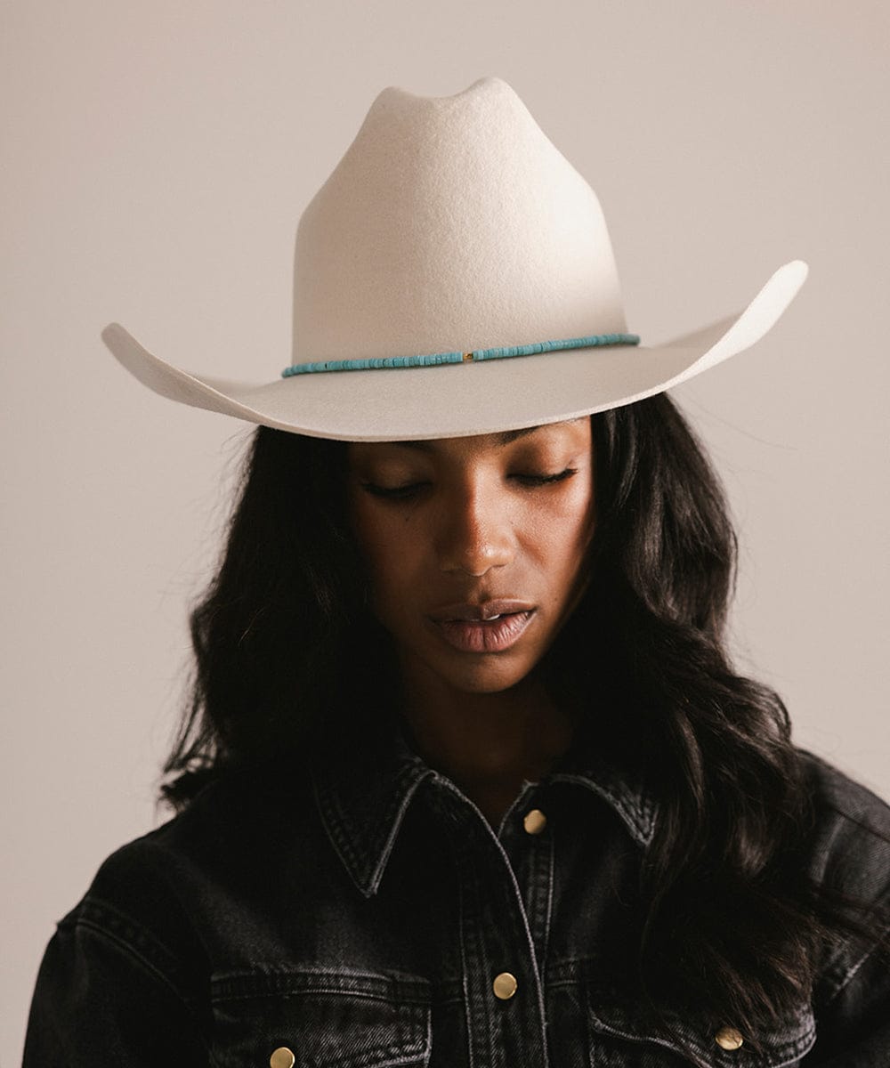 Person wearing a white cowboy hat with a blue band against a plain background #color_turquoise