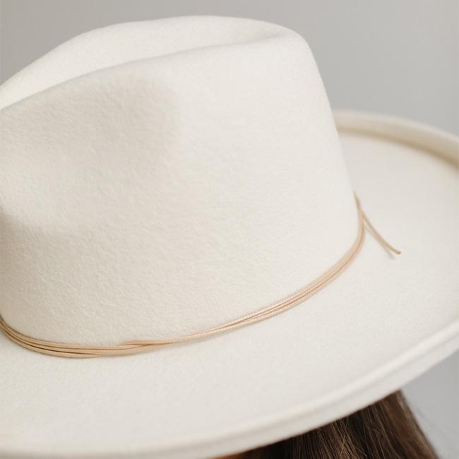 Close up image of a white cowboy hat with a tan hat band against a plain background #color_tan