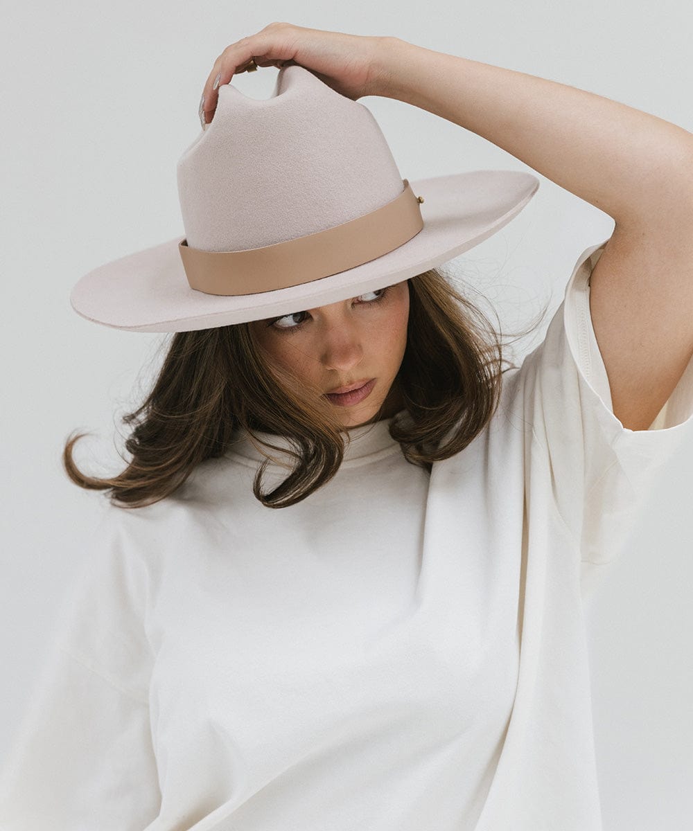 Woman wearing a cream hat with a wide tan leather band around the base, posing against a plain background #color_tan