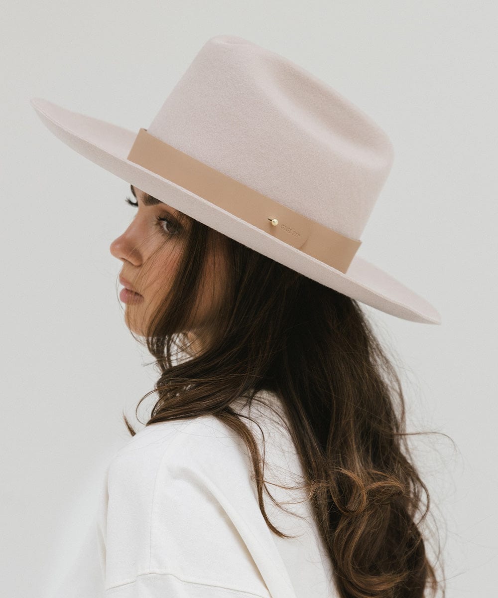 Woman wearing a cream hat with a wide tan leather band around the base, posing sideways against a plain background #color_tan