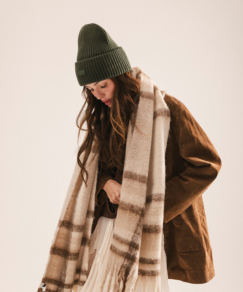 A woman wearing a dark green chunky ribbed beanie against a plain background #color_dark green