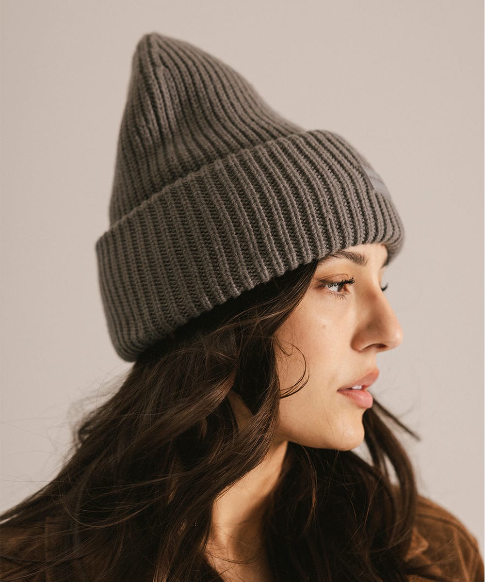 Woman wearing a grey knit beanie facing sideways against a neutral background #color_grey