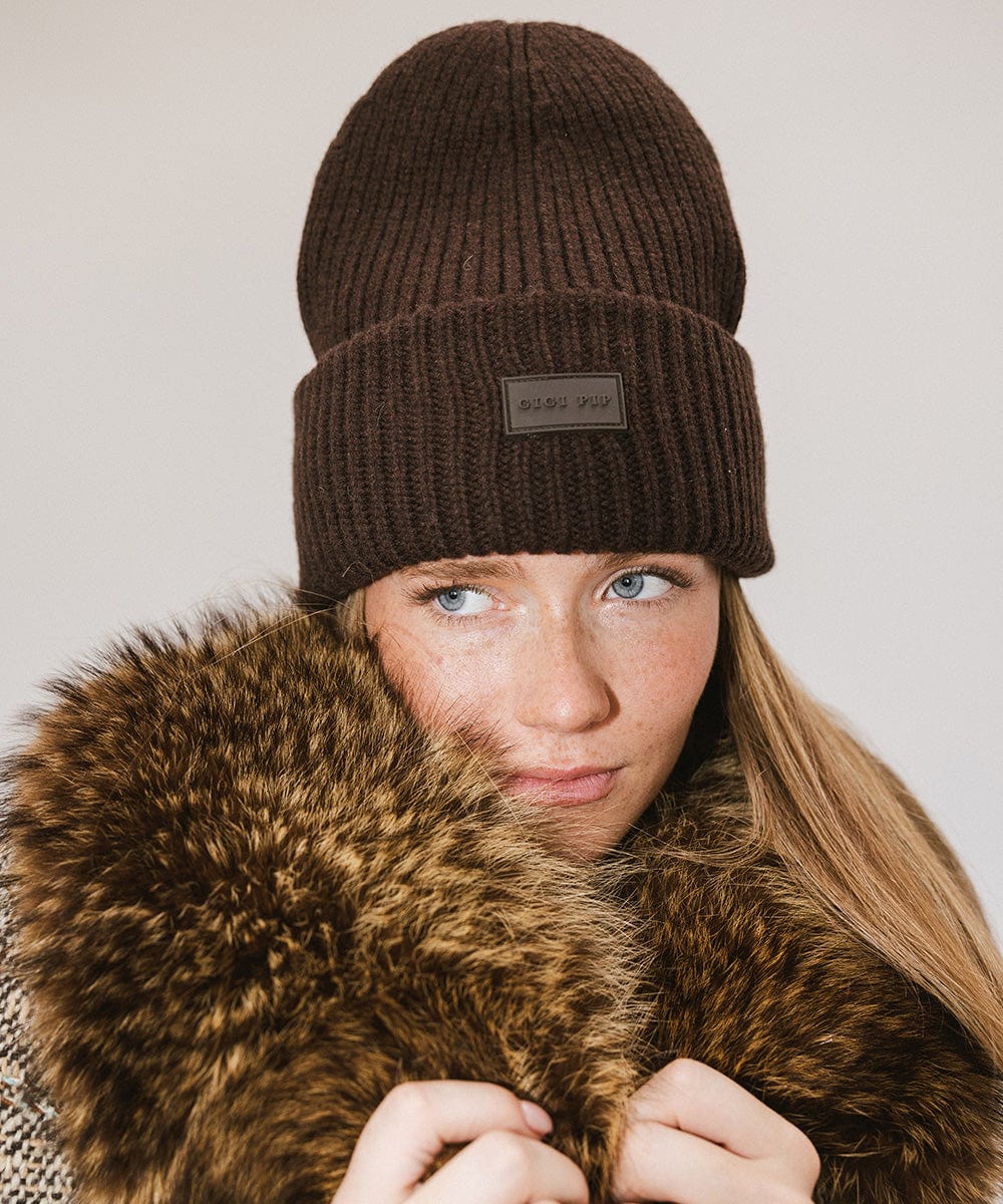 A woman wearing a dark brown chunky ribbed beanie against a plain background #color_dark brown