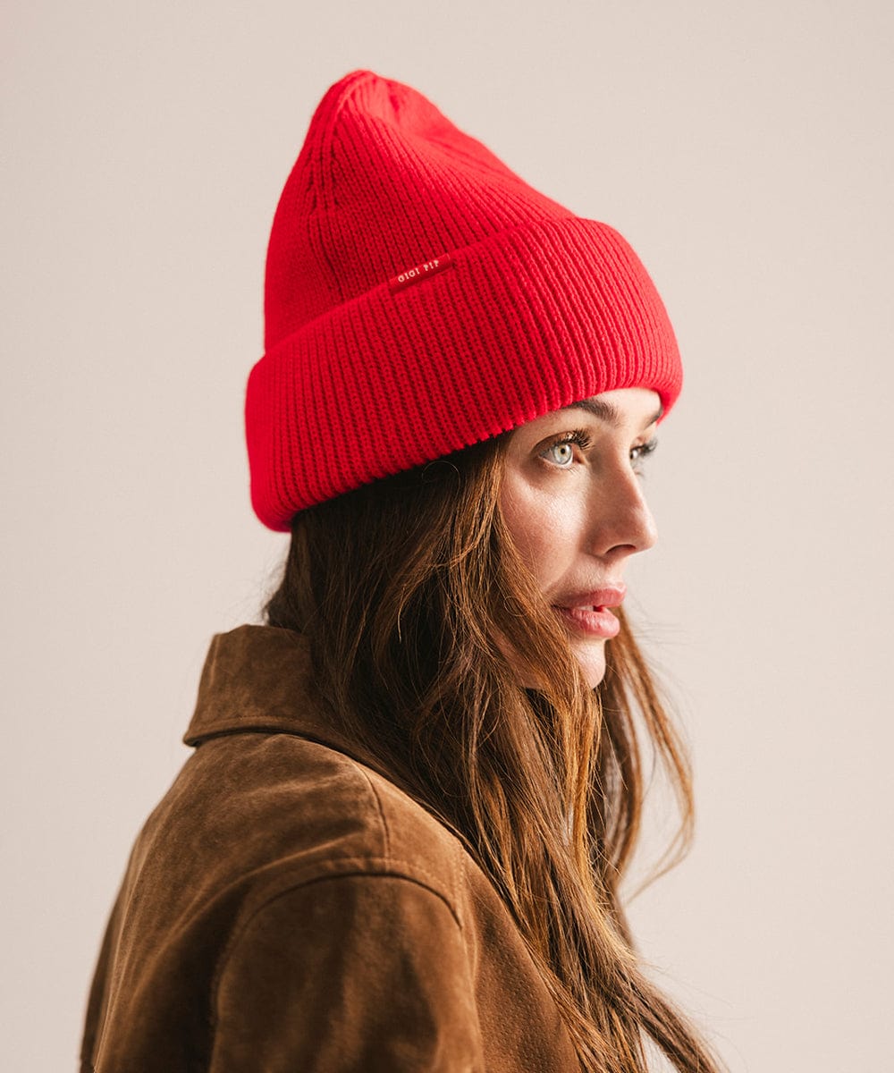 Person wearing a red beanie and brown jacket against a plain background #color_red