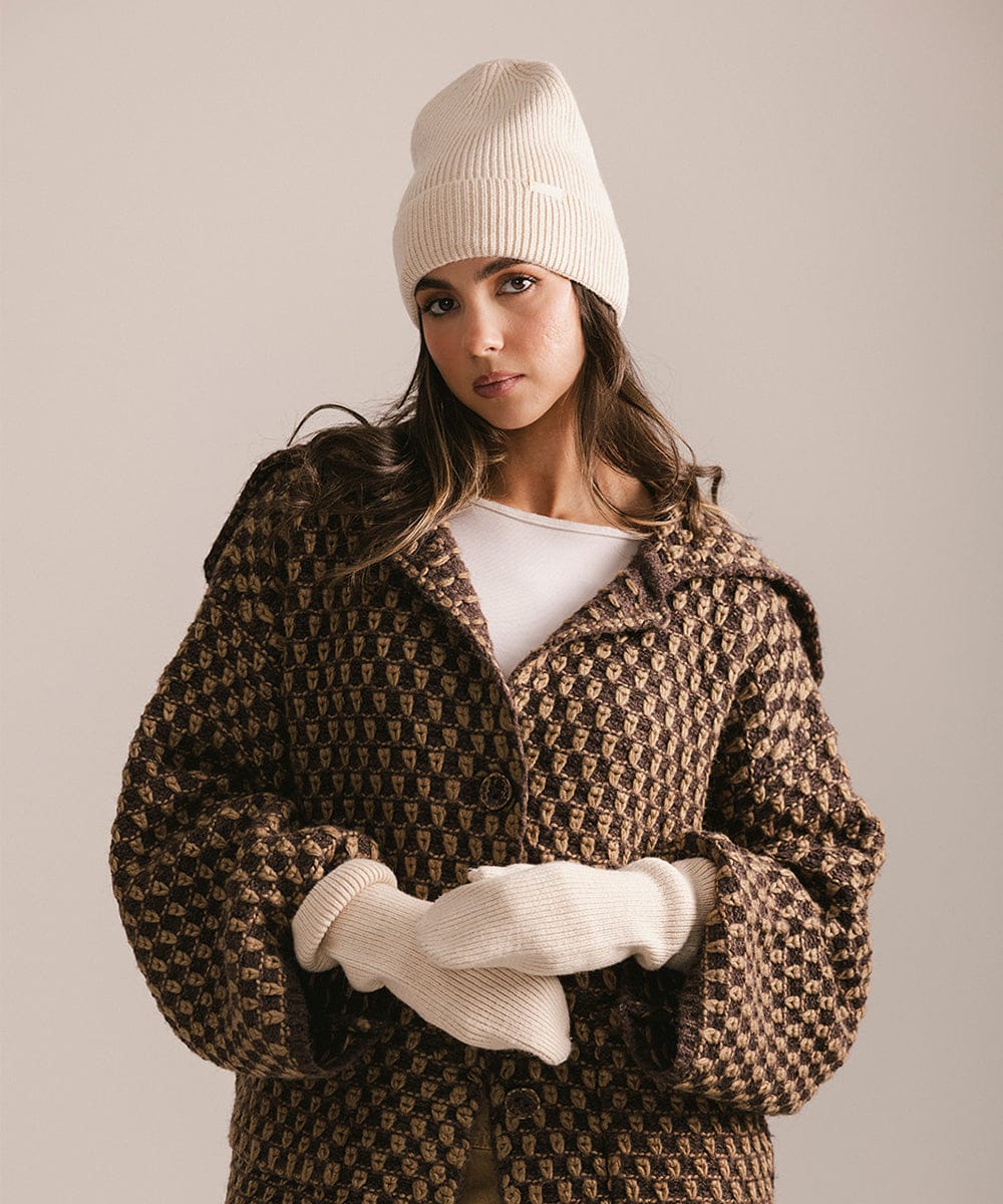 Woman wearing a patterned coat, white beanie, and gloves against a neutral background #color_taupe