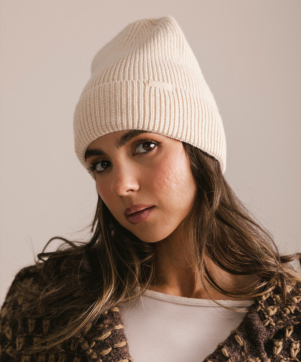 Woman wearing a beige knit beanie against a neutral background #color_taupe