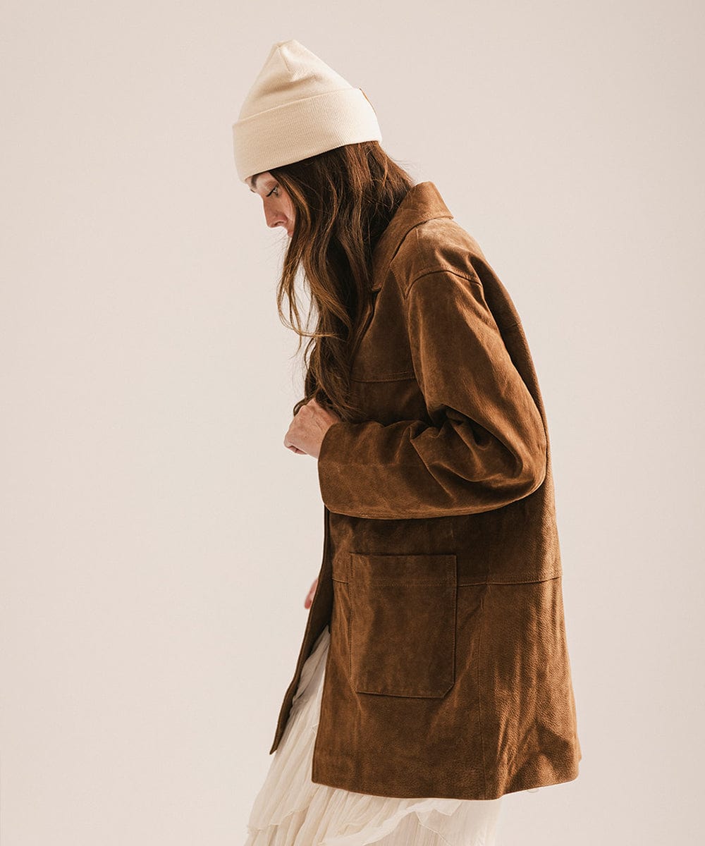 Person wearing a brown coat and beige beanie against a plain background #color_cream