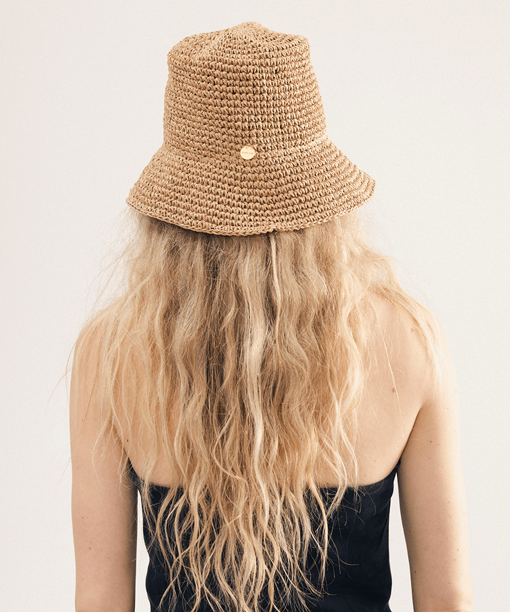 Person wearing a brown crochet packable bucket hat made from paper straw, displayed against a white background. #color_natural brown