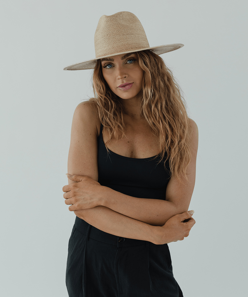 Woman wearing a beige straw hat and a black top against a plain background #color_toasted