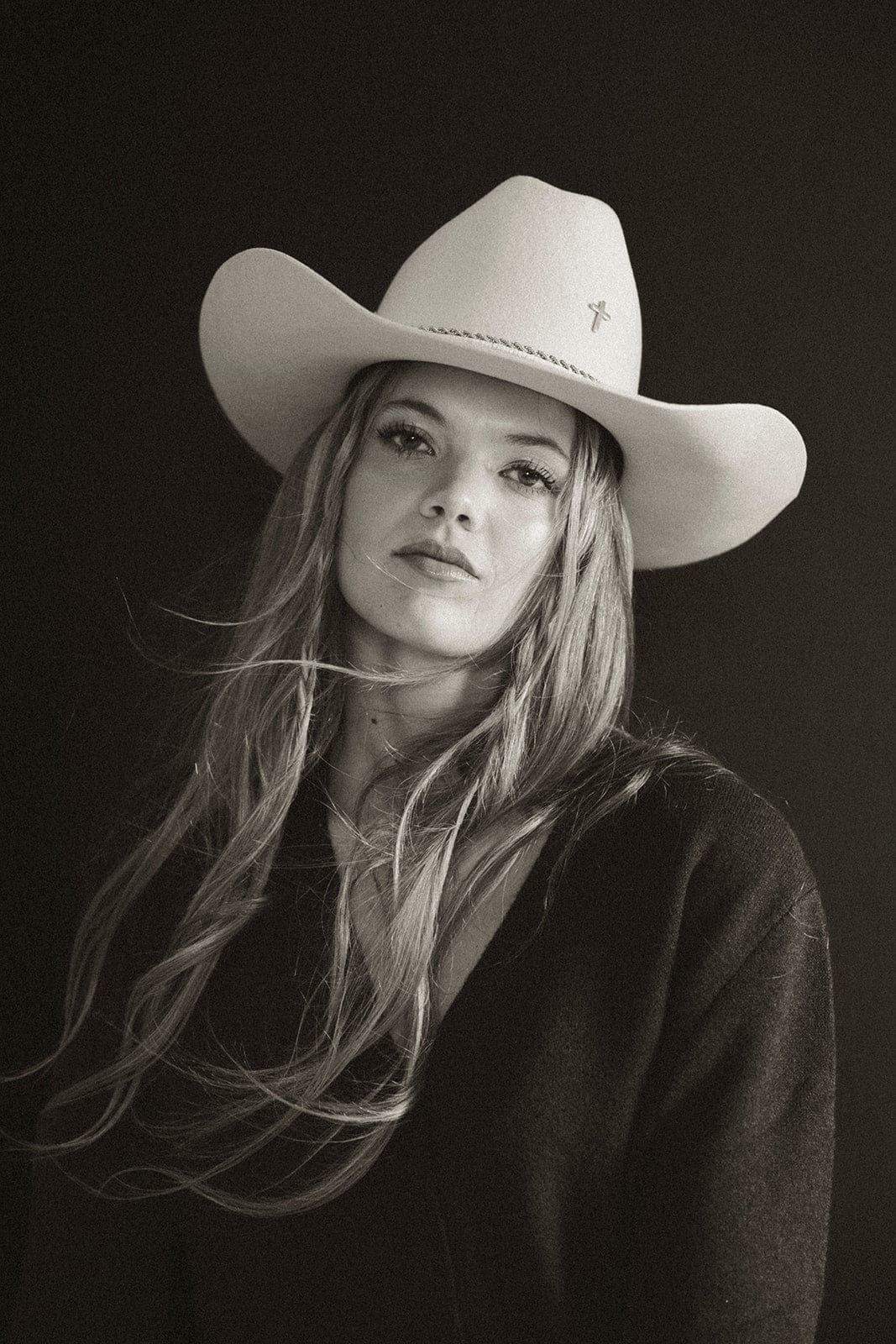 Black and white portrait of a woman wearing a cowboy hat against a dark background #color_silver