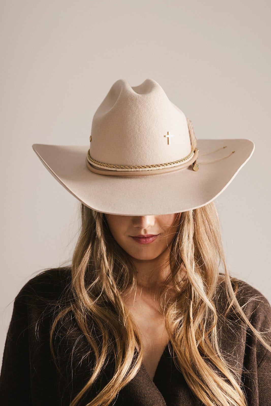 Person wearing a beige cowboy hat against a neutral background #color_gold