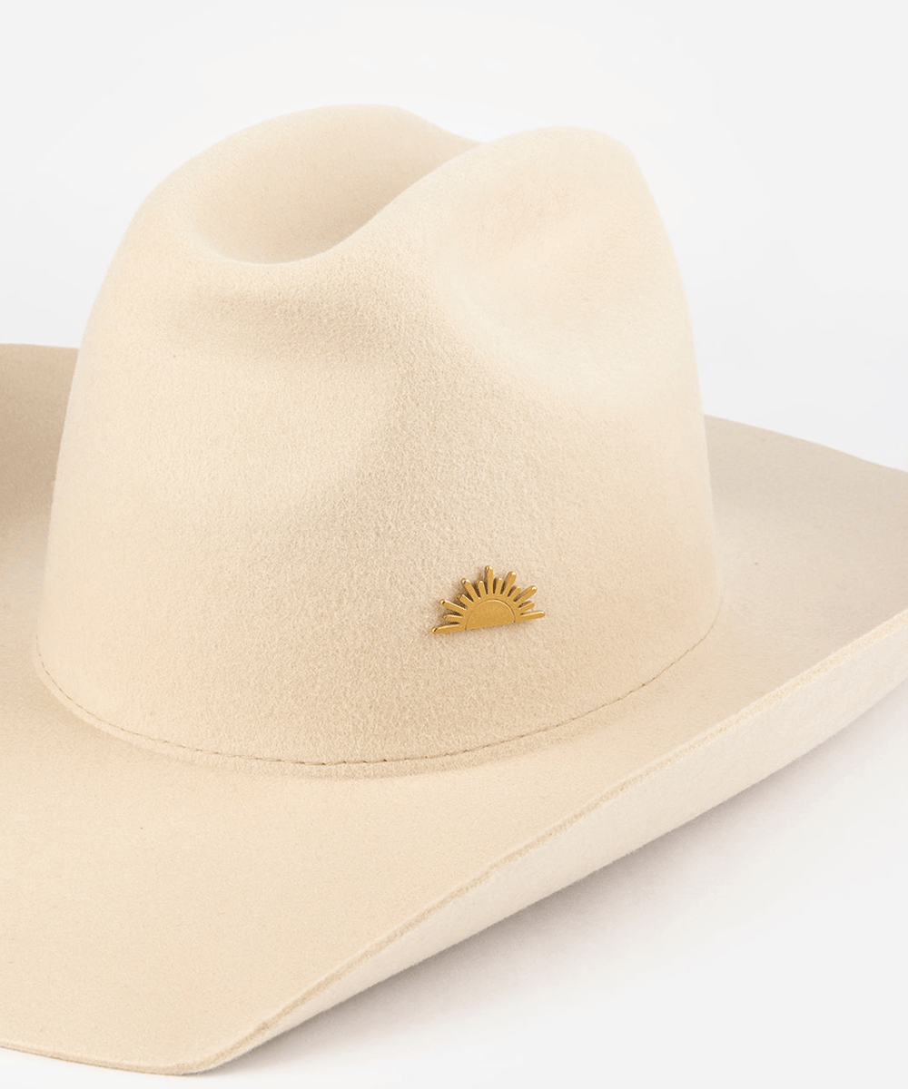 Pink cowboy hat with a gold sun-shaped hat pin on a white background #color_gold