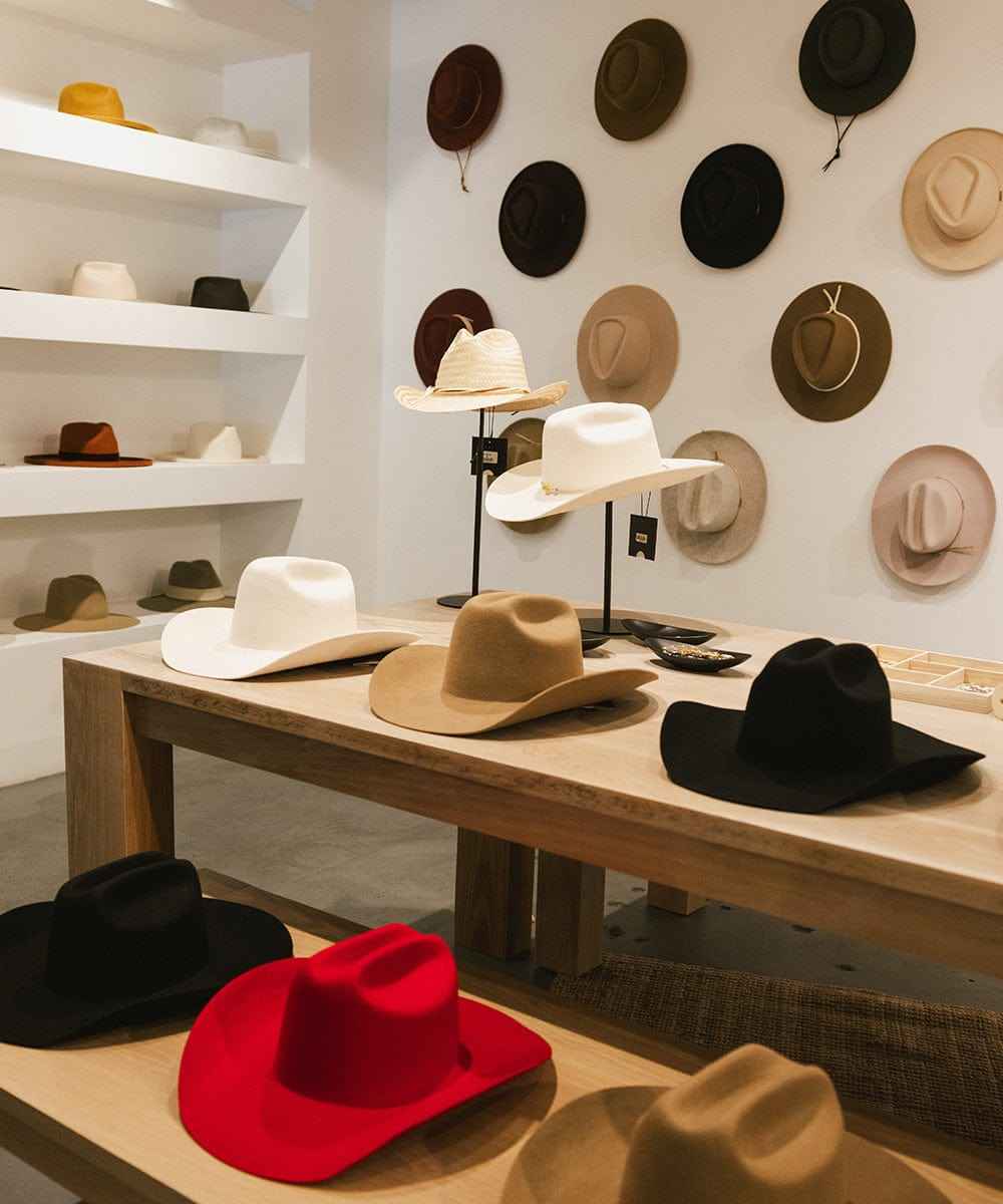 Display of various hats on a table and wall in a store setting