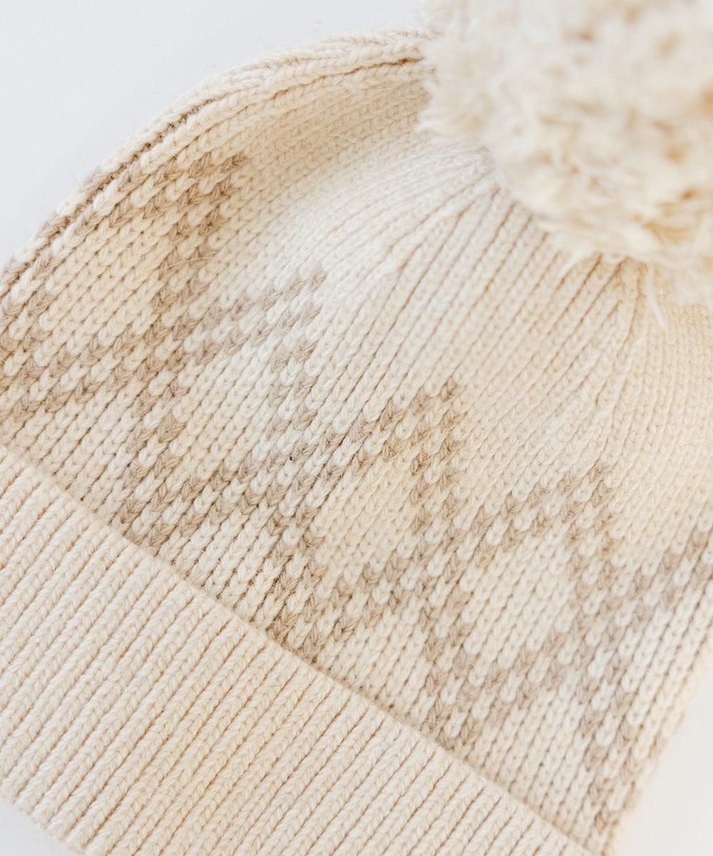 Close up image of a cream knit beanie with a pom-pom on a white background #color_cream