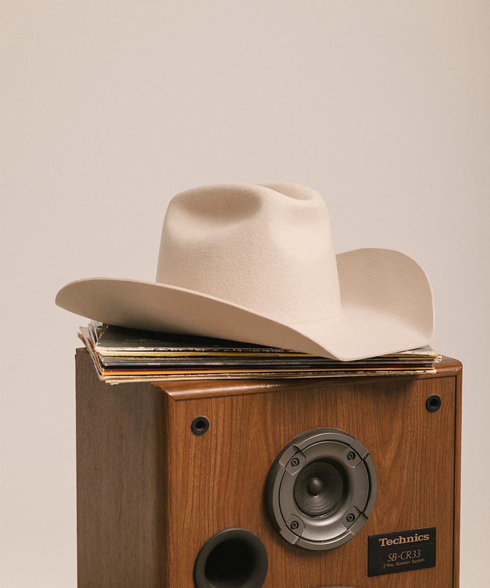 Cowboy hat on top of vinyl records with a Technics speaker system. #color_cream
