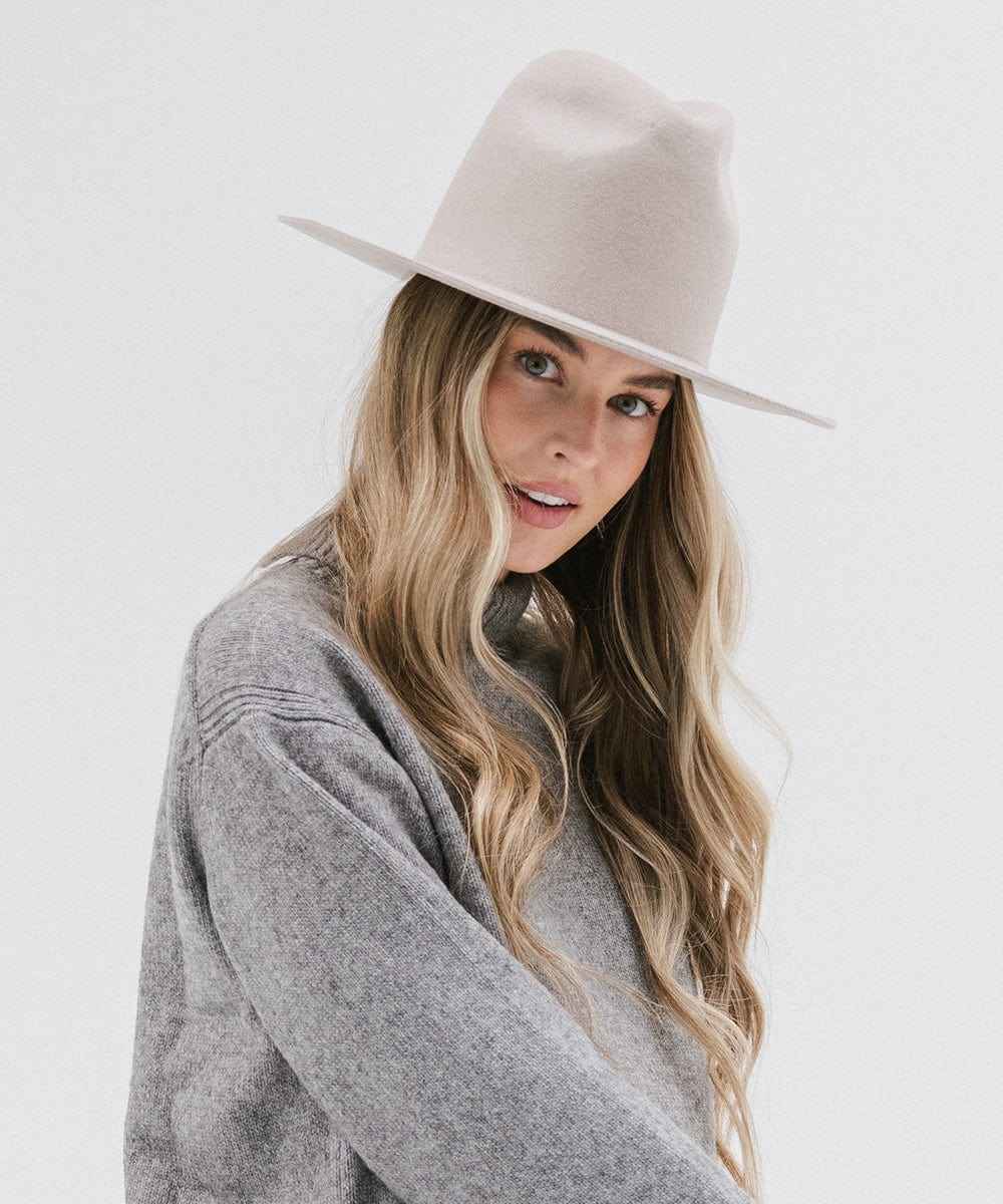 Woman wearing an ivory colored hat and grey sweater, posing sideways against a white background #color_ivory