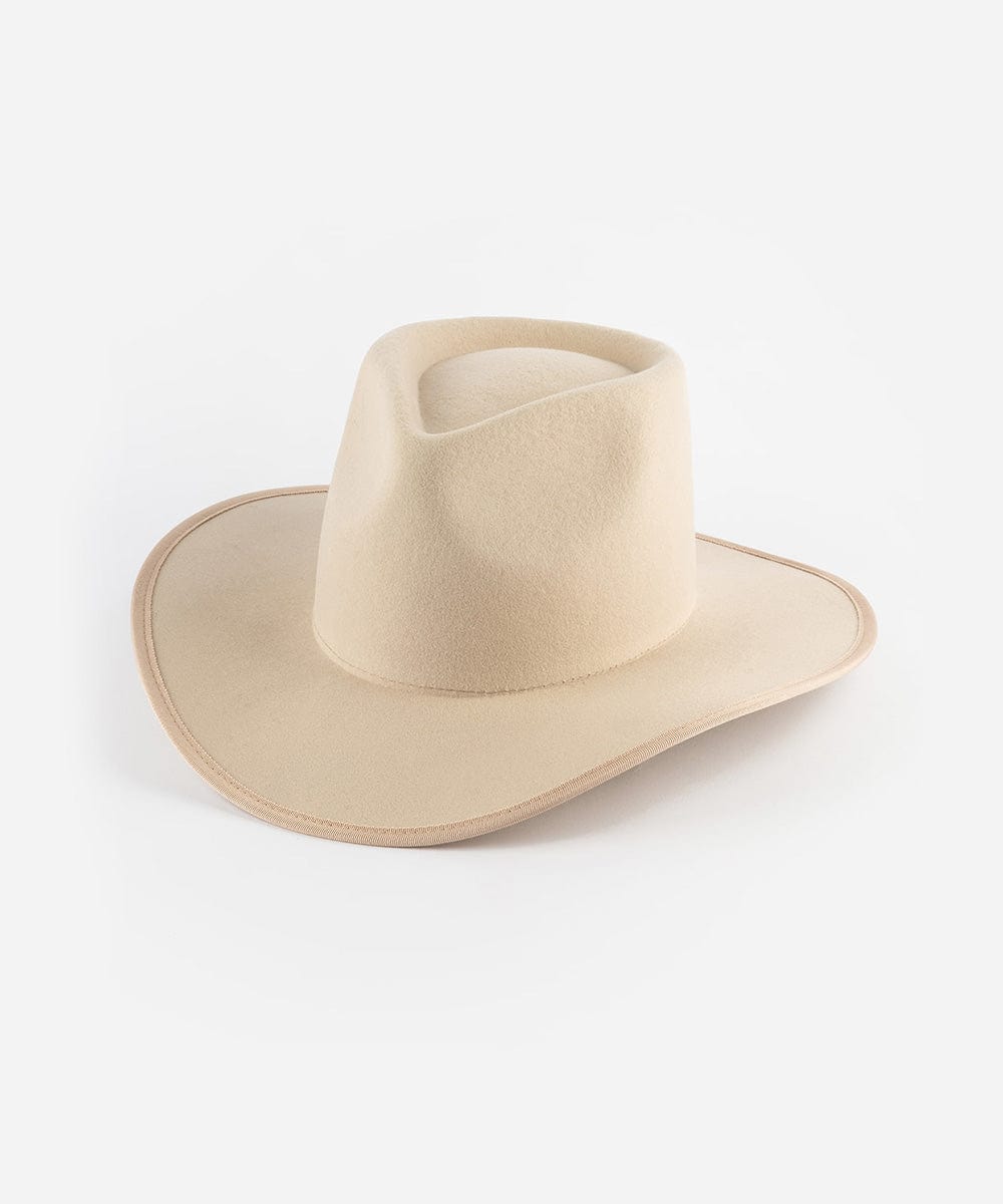 A cream felt Western hat with a teardrop-shaped crown and an angled brim, bound with a tonal grosgrain ribbon around the brim edge. #color_cream