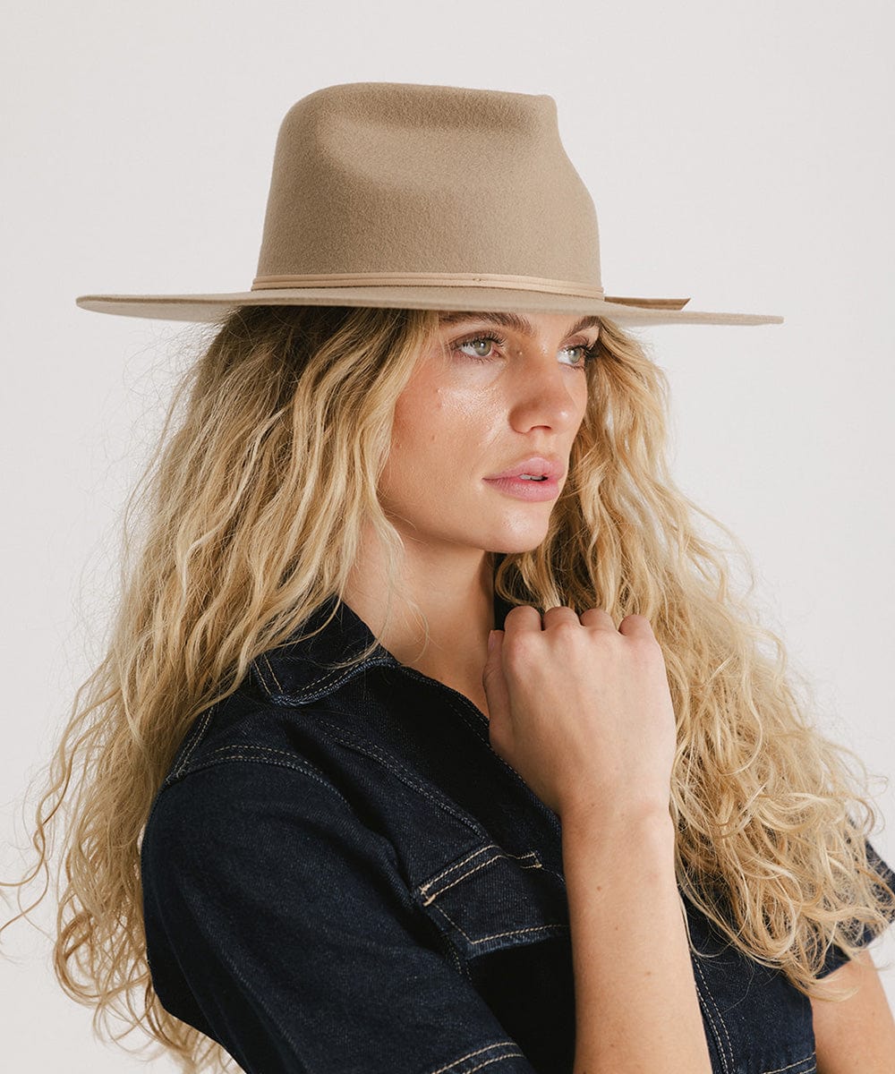 Woman with long blonde hair wearing a tan Emery Teardrop Fedora Hat and a denim shirt against a plain background  #color_tan